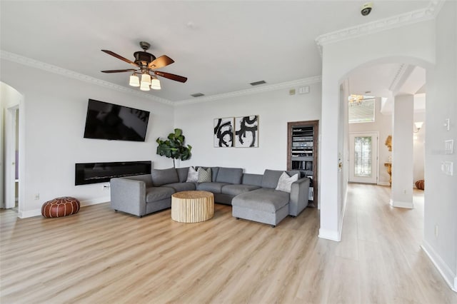 living room featuring ceiling fan, ornamental molding, and light wood-type flooring