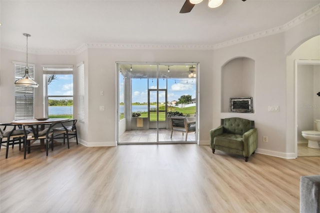 living room featuring hardwood / wood-style floors, a water view, ceiling fan, and ornamental molding