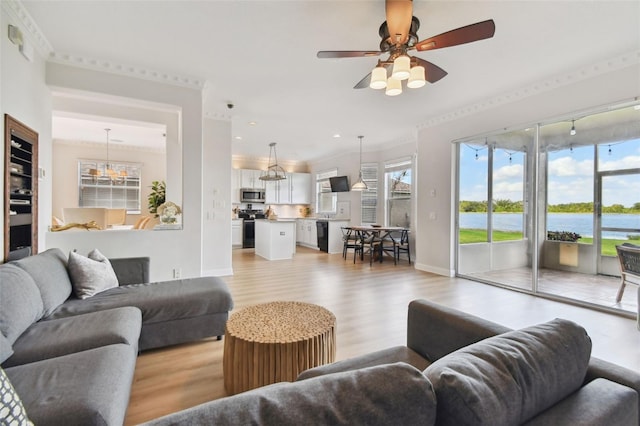 living room with a water view, ceiling fan, ornamental molding, and light hardwood / wood-style floors