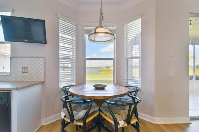 dining space featuring baseboards, light wood finished floors, plenty of natural light, and crown molding