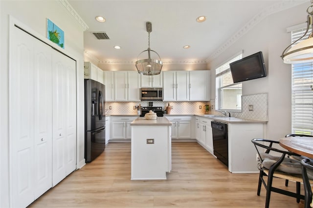 kitchen featuring white cabinetry, sink, decorative light fixtures, a kitchen island, and black appliances