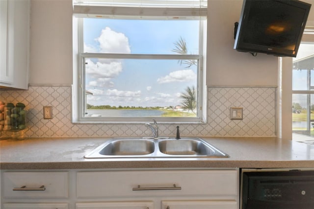 kitchen with decorative backsplash, sink, a water view, dishwasher, and white cabinetry