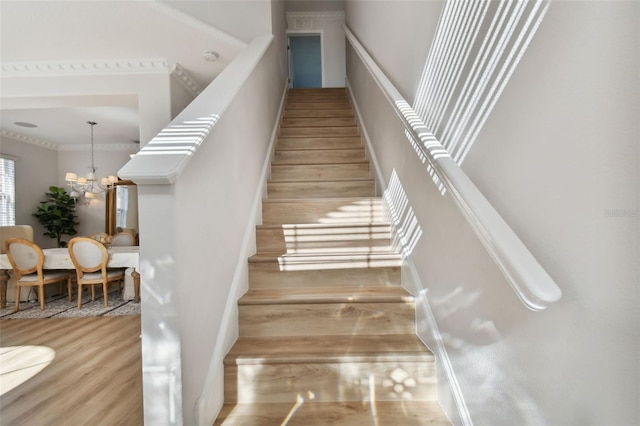 stairs with hardwood / wood-style flooring and a notable chandelier