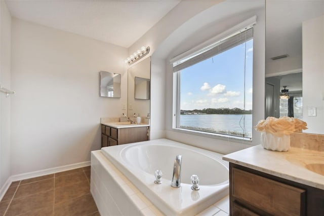 bathroom with vanity, ceiling fan, tiled tub, a water view, and tile patterned flooring