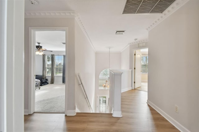 corridor with visible vents, crown molding, an upstairs landing, and wood finished floors