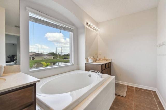 bathroom with tile patterned flooring, vanity, and tiled bath