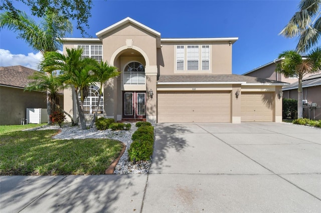 traditional-style house featuring an attached garage, concrete driveway, french doors, and stucco siding