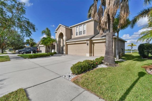 view of front of home with driveway, a front yard, an attached garage, and stucco siding