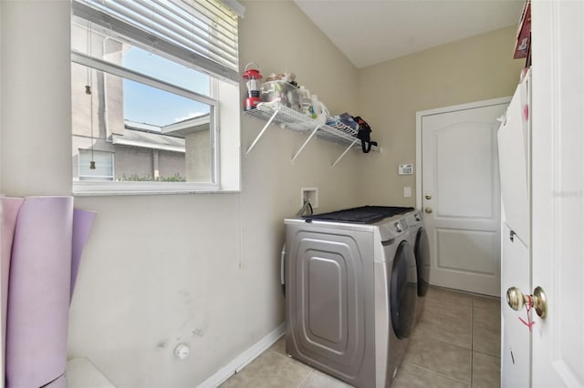 washroom with washing machine and dryer, laundry area, baseboards, and light tile patterned floors