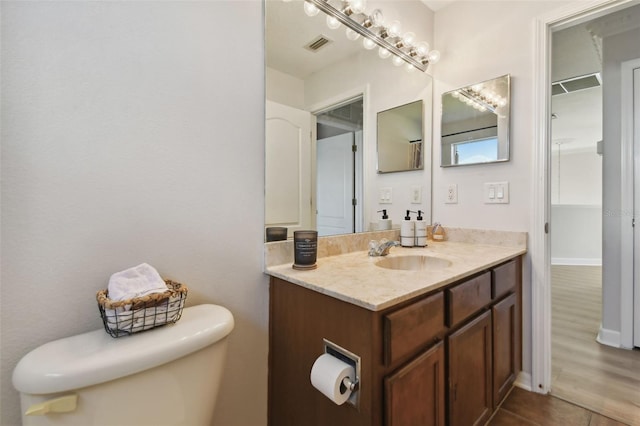 bathroom with baseboards, visible vents, vanity, and toilet