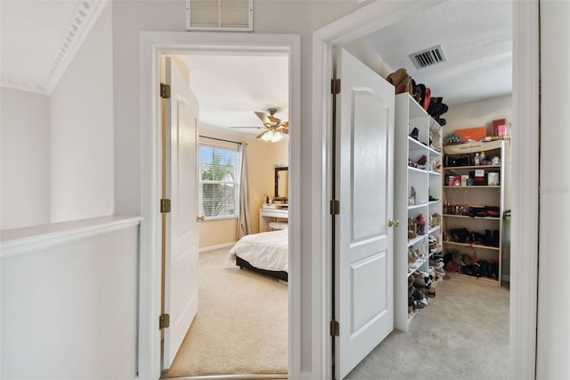 hallway with carpet, visible vents, and a textured ceiling