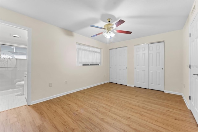 unfurnished bedroom featuring two closets, light hardwood / wood-style floors, ceiling fan, and ensuite bathroom