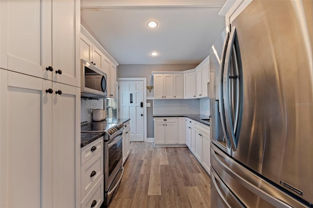 kitchen with backsplash, light hardwood / wood-style flooring, white cabinets, and stainless steel appliances