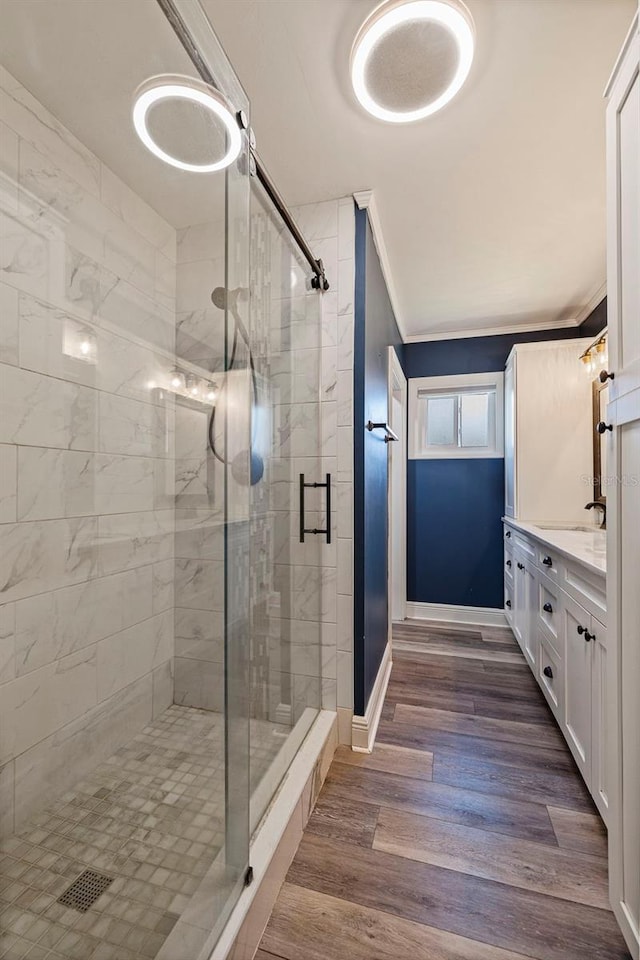 bathroom with vanity, a shower with shower door, wood-type flooring, and crown molding