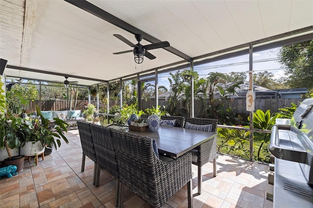 sunroom / solarium featuring beamed ceiling and ceiling fan