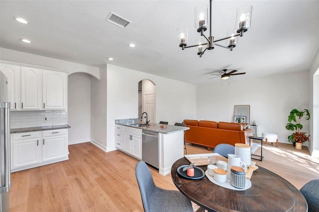 dining space featuring a textured ceiling, sink, ceiling fan with notable chandelier, and light wood-type flooring