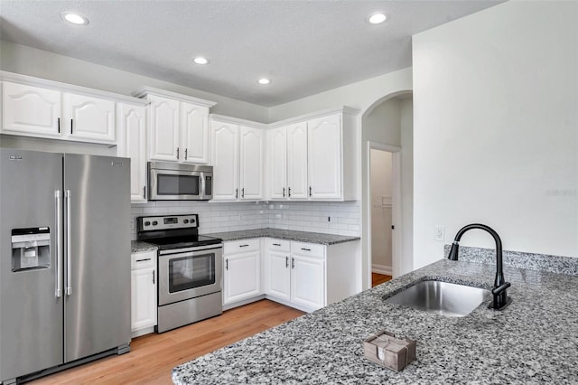 kitchen featuring sink, white cabinets, stone countertops, and appliances with stainless steel finishes