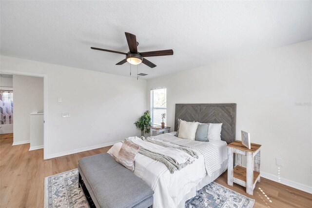 bedroom featuring ceiling fan, light hardwood / wood-style floors, and a textured ceiling