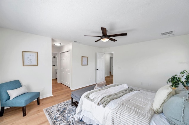 bedroom with a closet, ceiling fan, light hardwood / wood-style flooring, and a textured ceiling