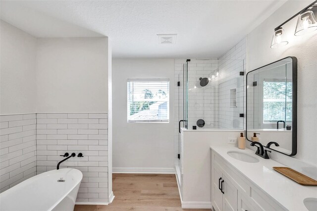 bathroom featuring a textured ceiling, vanity, independent shower and bath, tile walls, and hardwood / wood-style flooring