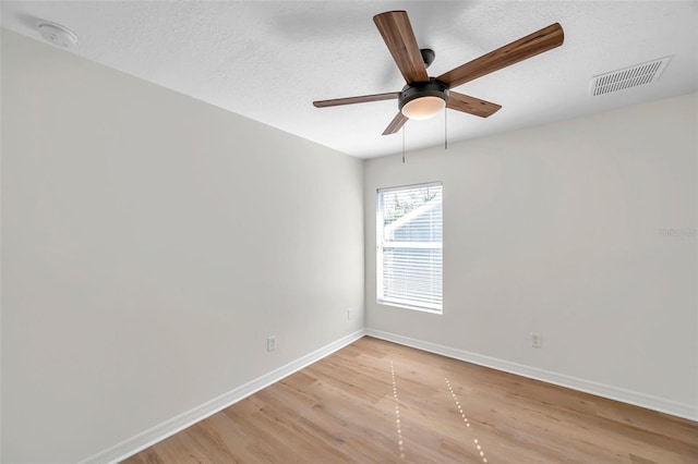 empty room with ceiling fan, light wood-type flooring, and a textured ceiling