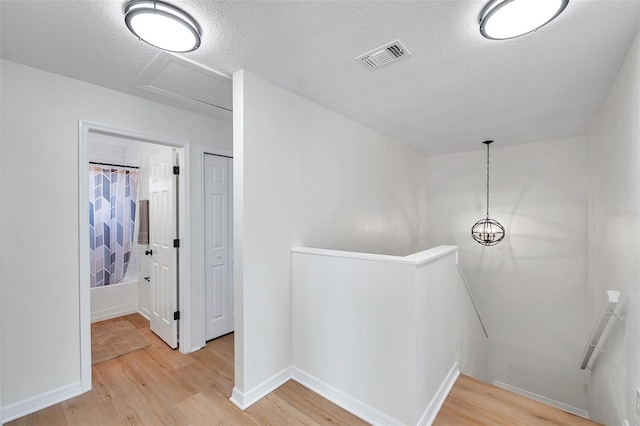 hall with light wood-type flooring and a textured ceiling