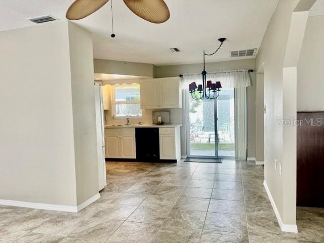 kitchen with pendant lighting, dishwasher, white cabinetry, and ceiling fan with notable chandelier