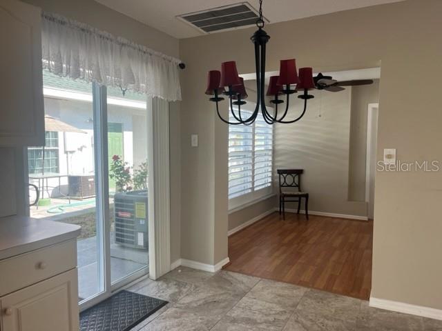 unfurnished dining area with ceiling fan with notable chandelier and light hardwood / wood-style floors