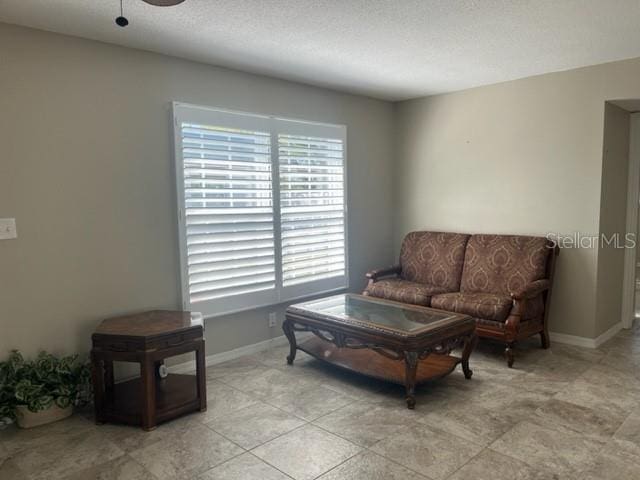 sitting room with ceiling fan, light tile patterned flooring, and a textured ceiling