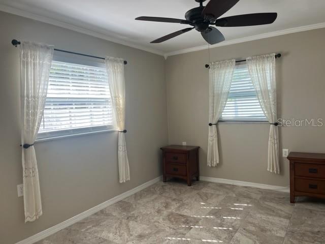 unfurnished room with ceiling fan and crown molding