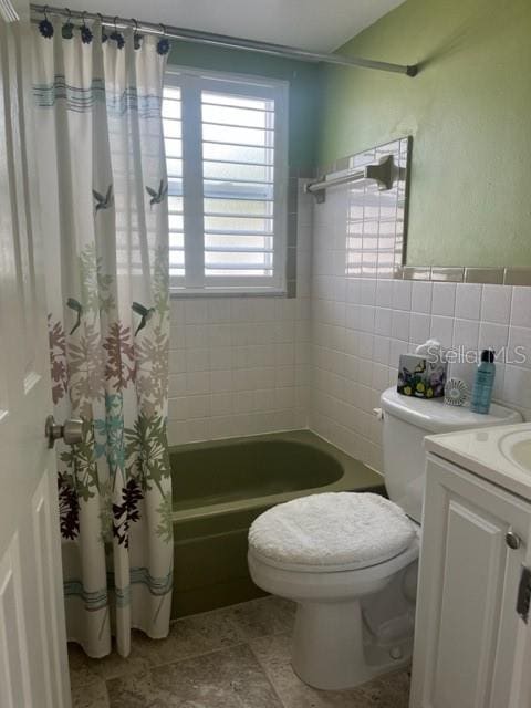 full bathroom with shower / bath combo, vanity, tile walls, and toilet