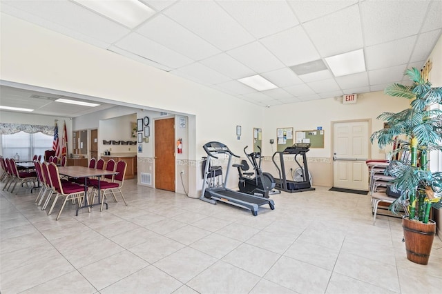 workout area with a paneled ceiling and tile patterned flooring