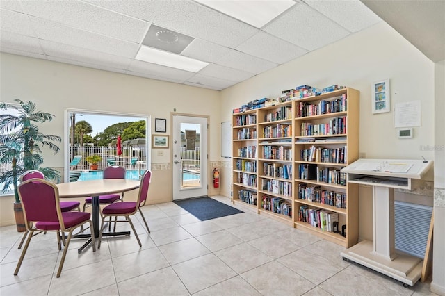 dining area with a drop ceiling and light tile patterned flooring