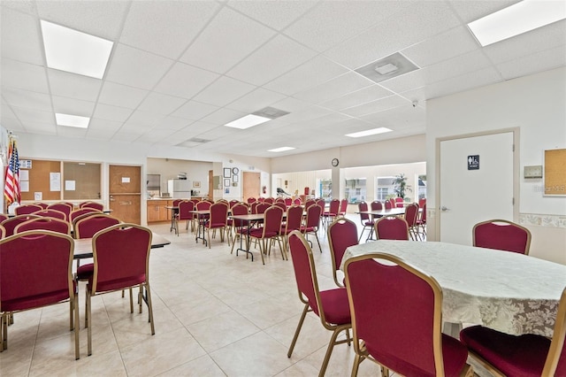 dining area with a paneled ceiling and light tile patterned floors