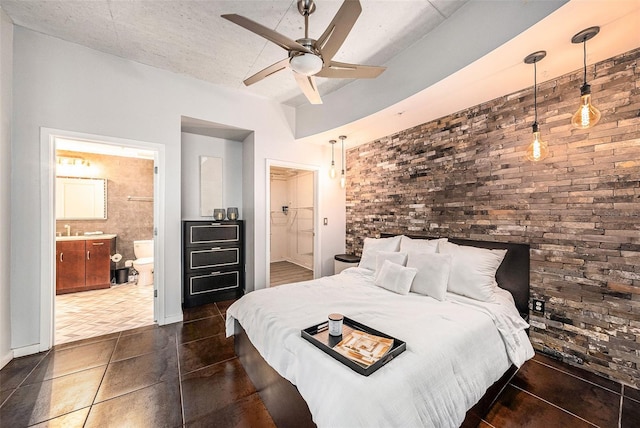 bedroom featuring ensuite bath, brick wall, ceiling fan, sink, and dark tile patterned flooring