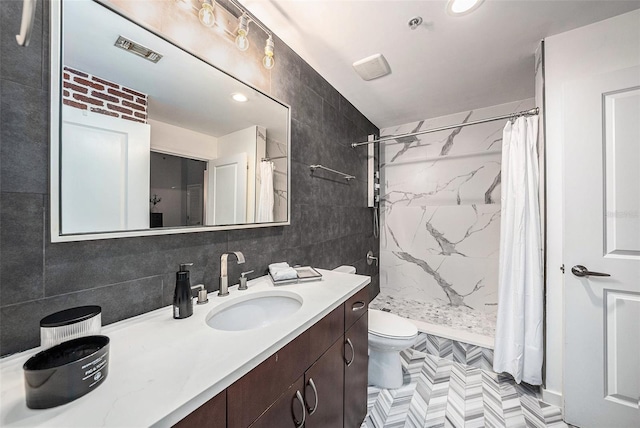 bathroom with walk in shower, vanity, toilet, and tile walls