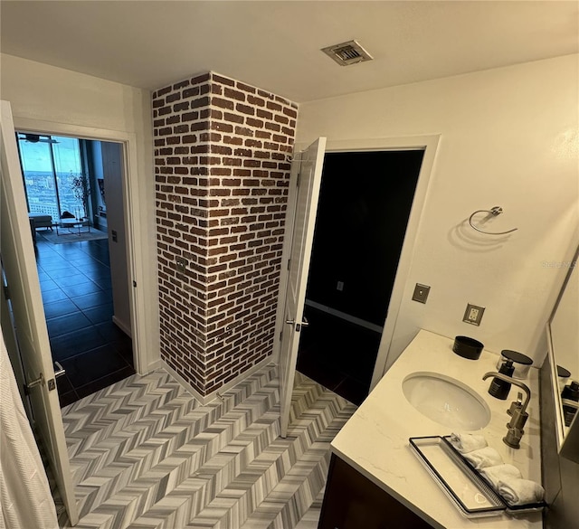 bathroom with brick wall, tile patterned floors, and vanity