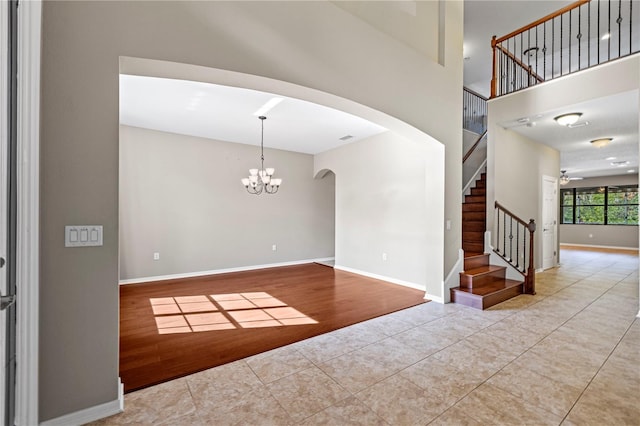 spare room featuring ceiling fan with notable chandelier and light wood-type flooring