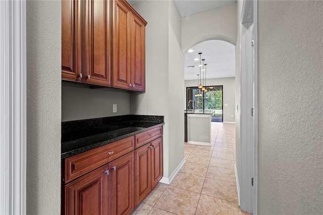 interior space with light tile patterned floors, hanging light fixtures, and dark stone counters