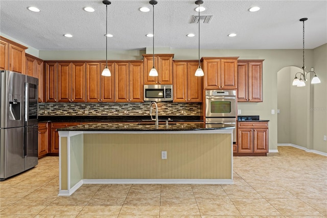 kitchen with pendant lighting, sink, decorative backsplash, an island with sink, and appliances with stainless steel finishes