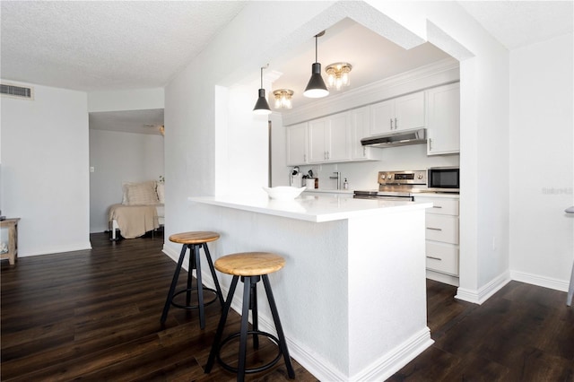 kitchen featuring appliances with stainless steel finishes, hanging light fixtures, white cabinets, a kitchen bar, and kitchen peninsula