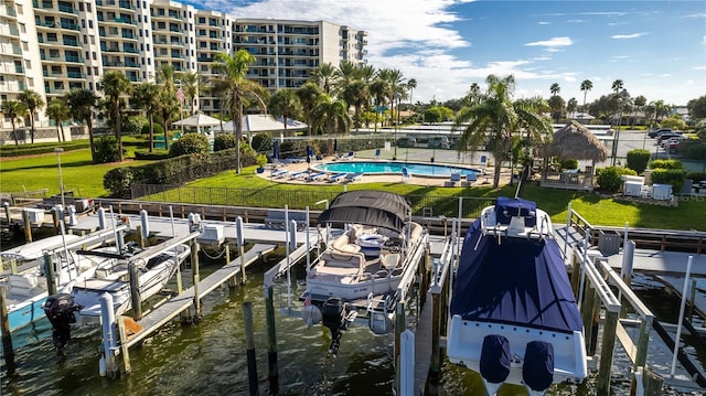 view of dock featuring a water view, a community pool, and a lawn