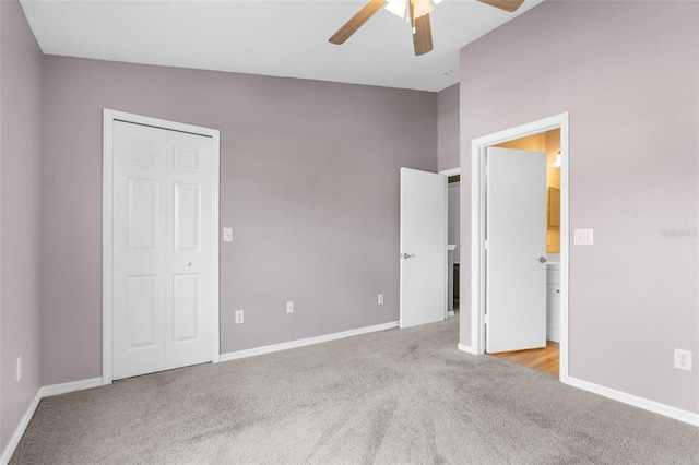 unfurnished bedroom with ceiling fan, ensuite bathroom, light carpet, and vaulted ceiling