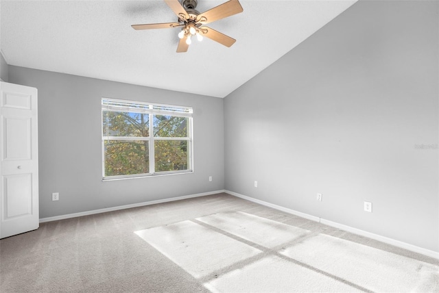 carpeted spare room with ceiling fan and vaulted ceiling