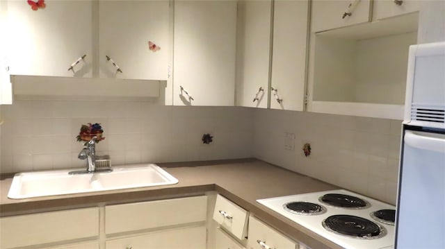 kitchen featuring white cabinetry, white cooktop, tasteful backsplash, and sink