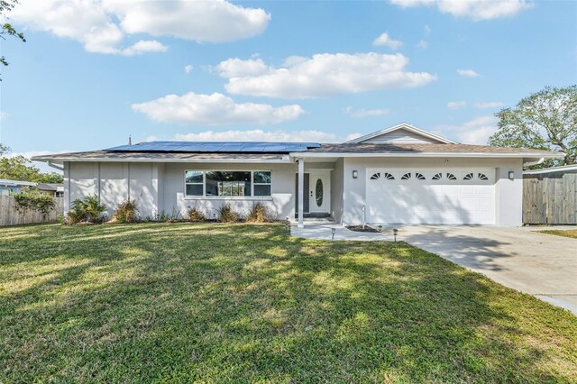 ranch-style home with a front yard, solar panels, and a garage