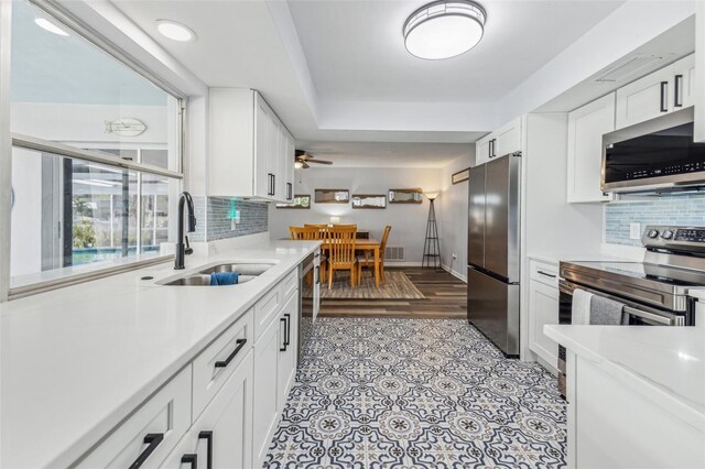 kitchen featuring decorative backsplash, appliances with stainless steel finishes, ceiling fan, sink, and white cabinetry