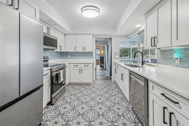 kitchen featuring appliances with stainless steel finishes, tasteful backsplash, white cabinetry, and sink