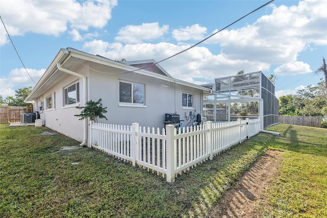 view of home's exterior featuring a lanai, a lawn, and central AC unit