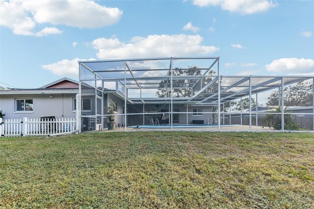 back of property with glass enclosure and a yard